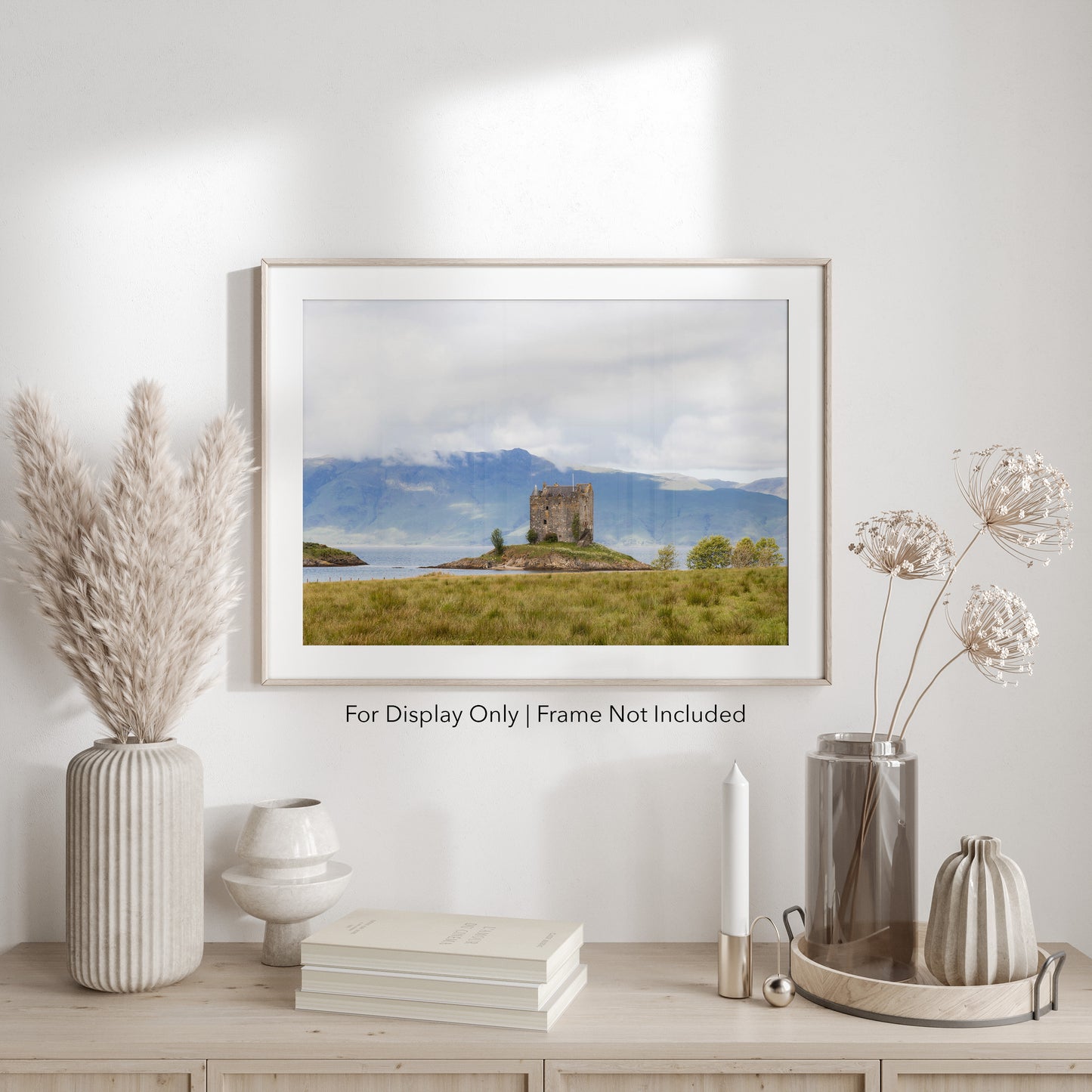 Castle Stalker on a small island in Loch Laich, Scottish Highlands, surrounded by mountains and water.