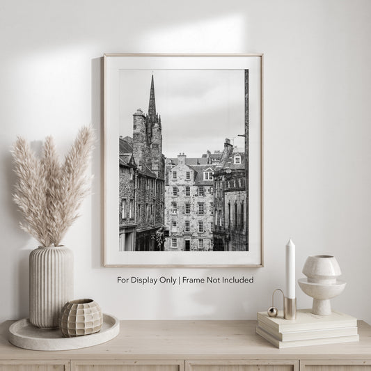 Black and white photograph of an Edinburgh street with historic stone architecture and a church spire.