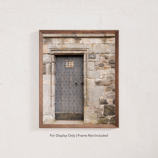 Rustic wooden door with iron studs set in a weathered stone wall, photographed in Edinburgh, Scotland.