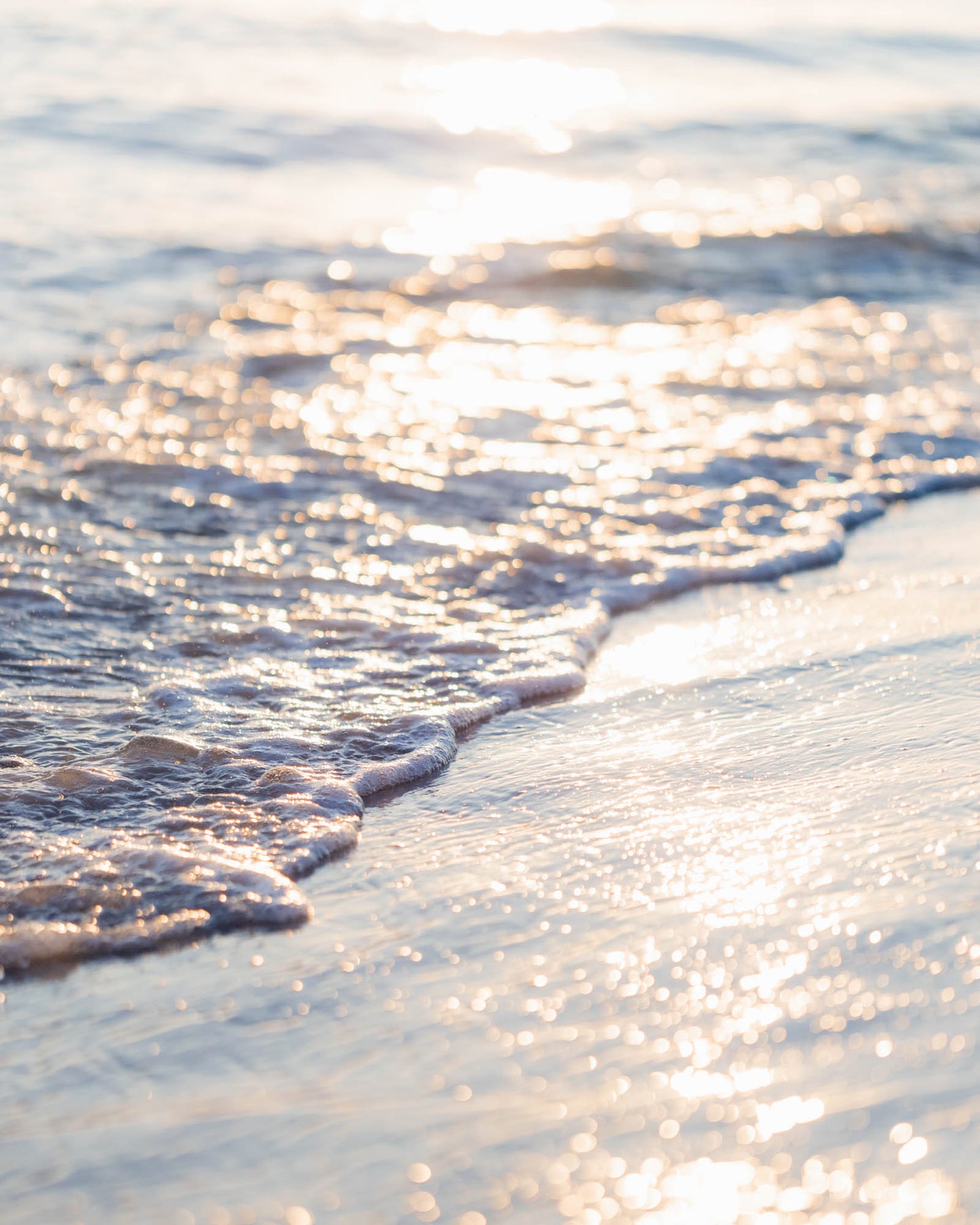 Ocean waves washing ashore in golden sunset light, coastal beach photography wall art.