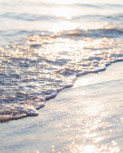 Ocean waves washing ashore in golden sunset light, coastal beach photography wall art.