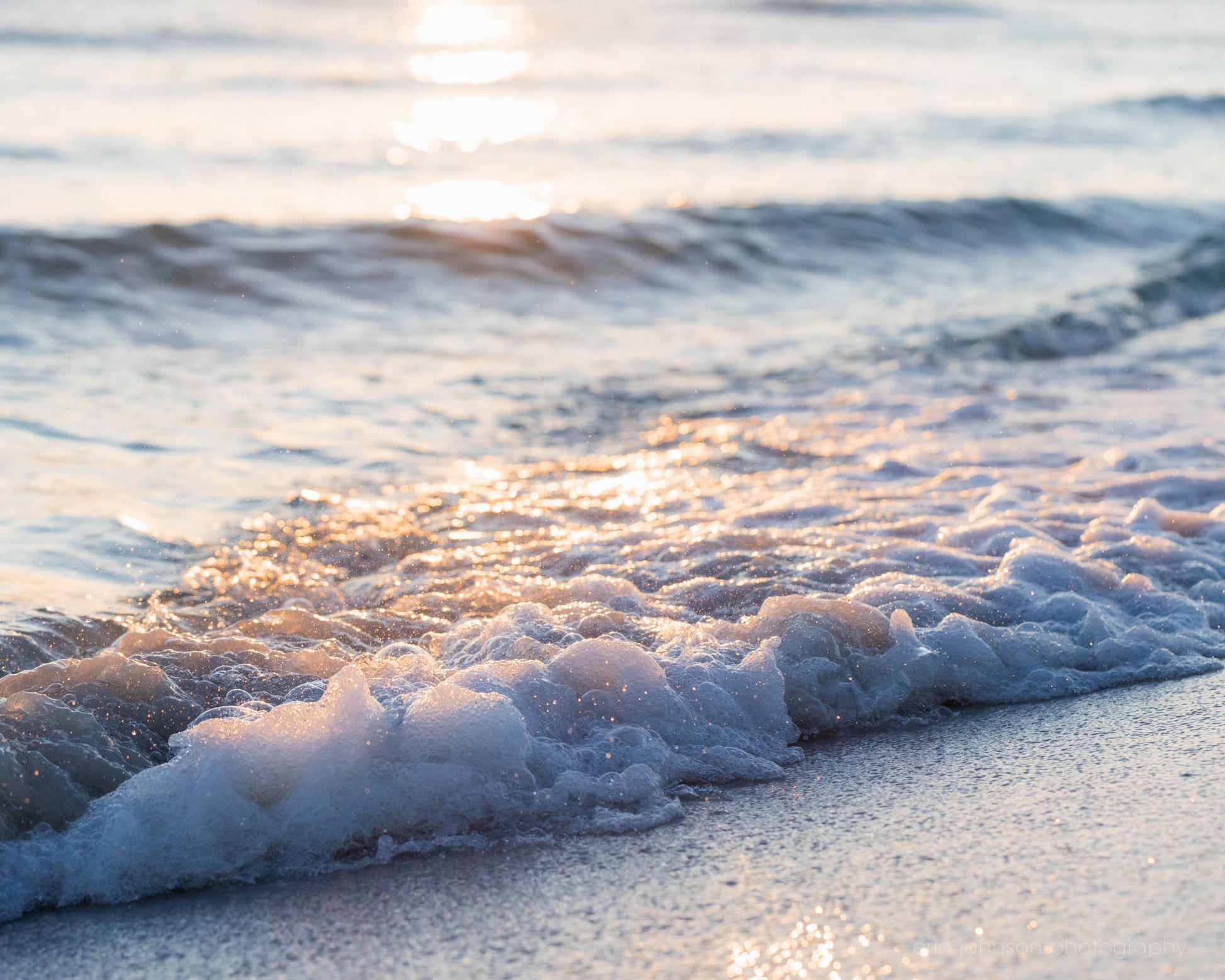 Foamy wave rolling onto the sandy beach in Destin, Florida, glowing in soft Gulf Coast sunlight.