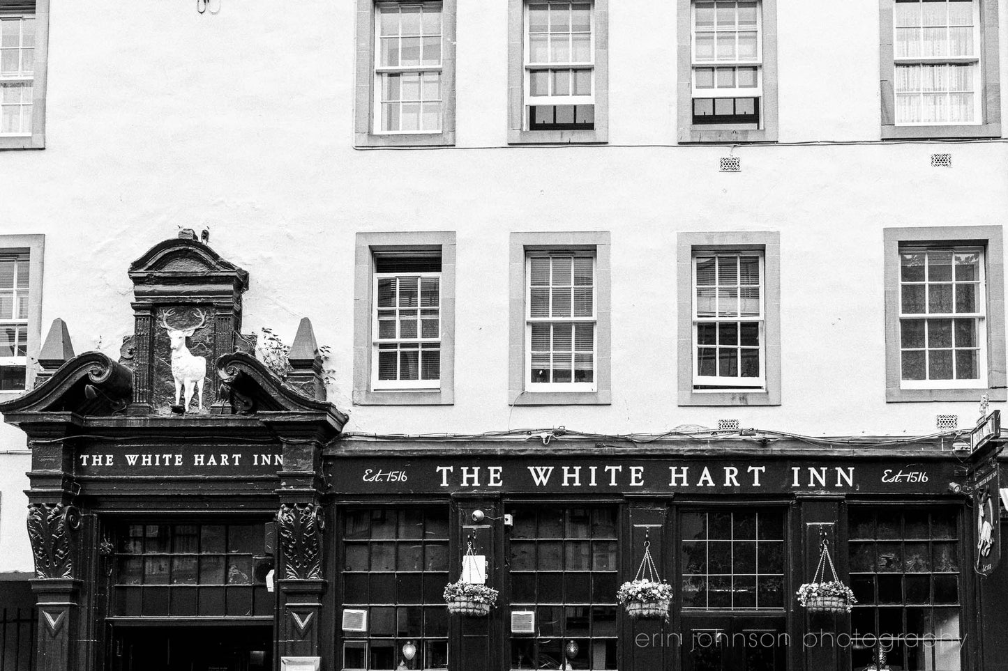 Black and white photo of The White Hart Inn pub with decorative elements.