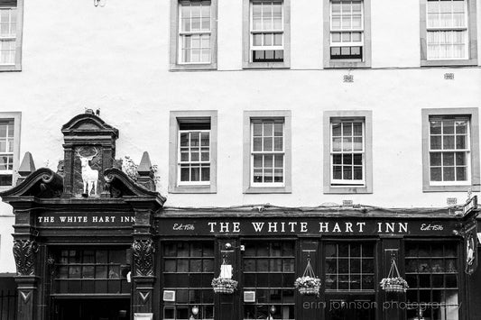 Black and white photo of The White Hart Inn pub with decorative elements.