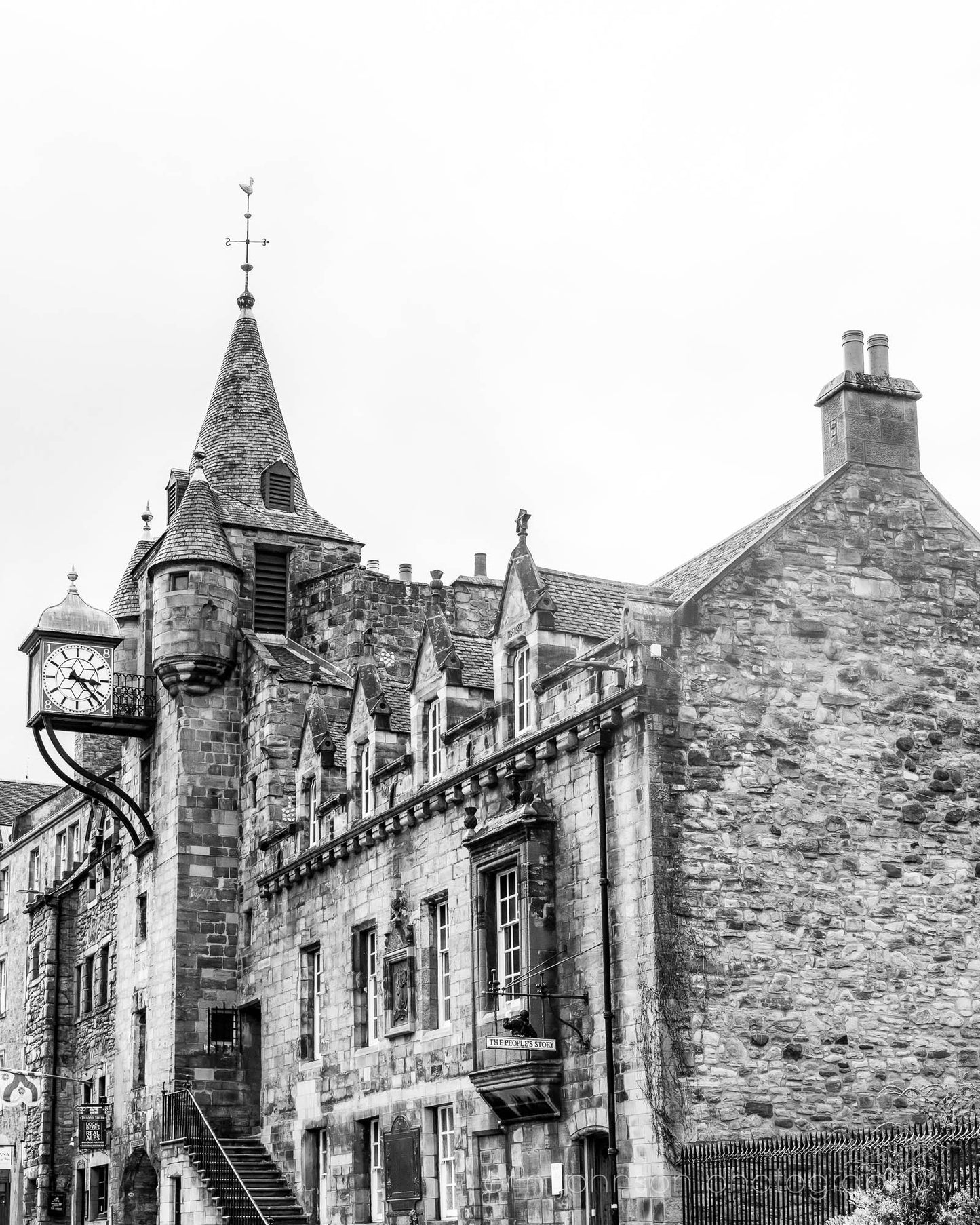 Black and white photograph of the Canongate Tolbooth clock tower on Edinburgh’s Royal Mile, historic stone building with Gothic details.