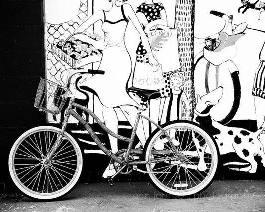 a black and white photo of a woman on a bike