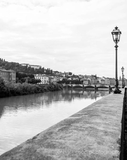 a black and white photo of a river and a lamp post