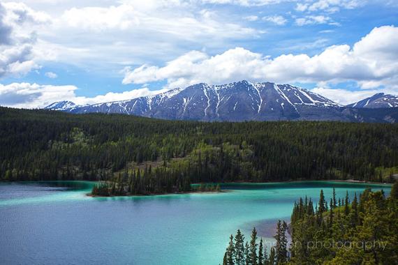 a lake surrounded by trees and mountains under a blue sky