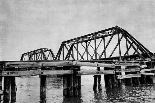 a black and white photo of a bridge over water