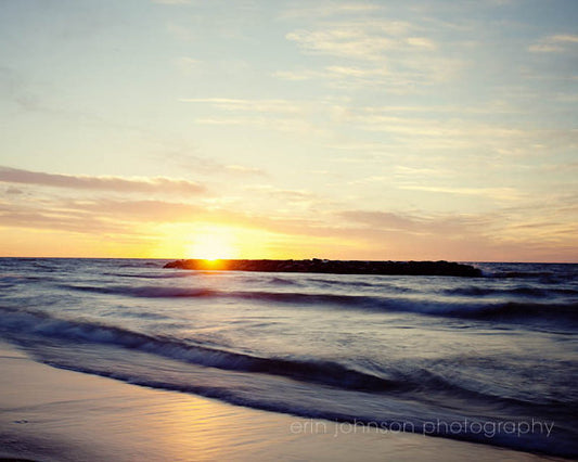 the sun is setting over the water at the beach