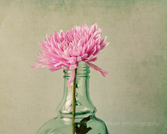 a pink flower in a green glass bottle