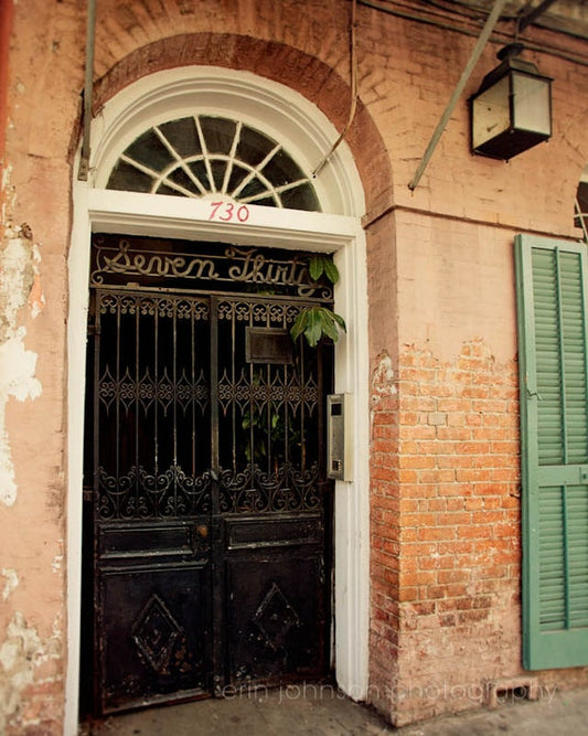 an old brick building with a black door and green shutters