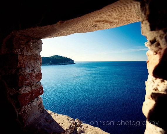 a view of the ocean from a window in a stone wall