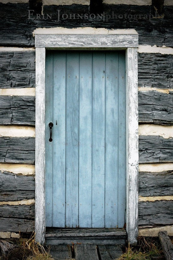 a blue door sits in front of a log cabin