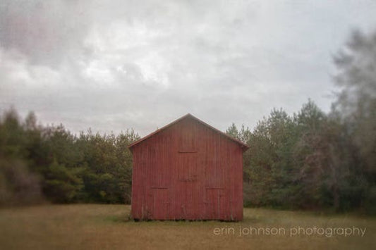 a red barn sitting in the middle of a field