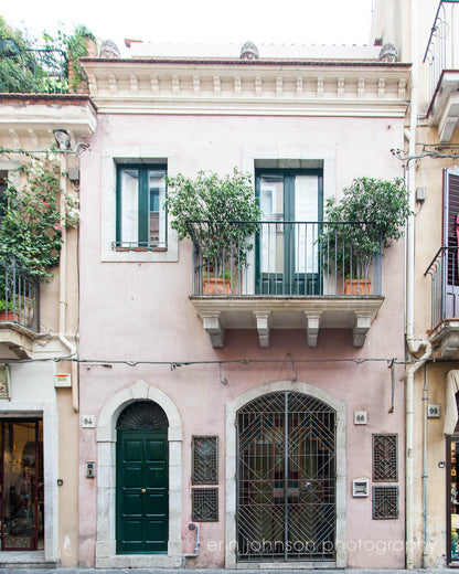 a pink building with green doors and windows