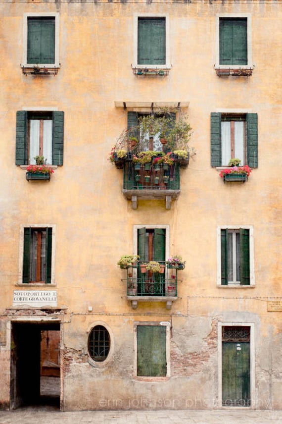 an old building with green shutters and flowers on the windows