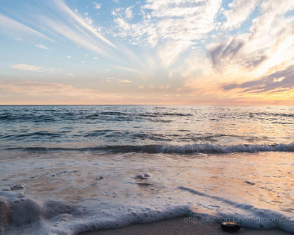 A photograph of a serene beach sunset landscape with gentle waves reaching the shore, Florida Gulf Coast.