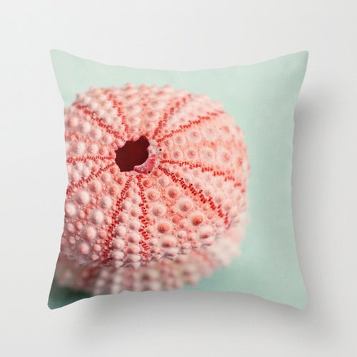 a pink flower on a green pillow on a white wall